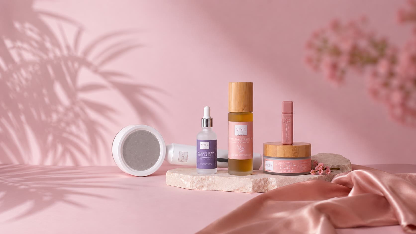 Natural hair and skin care product collection by Nola By Gala — hair serum, magnesium treatment, eyelash serum, and shower filter arranged on stone pedestals